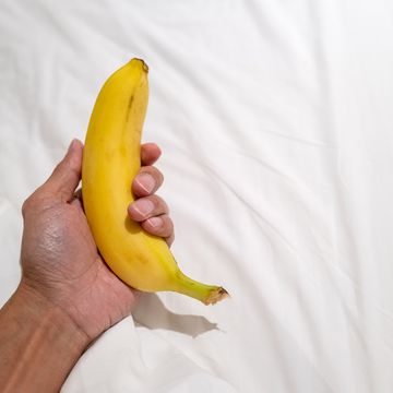 人的手拿著香蕉在白色床單前