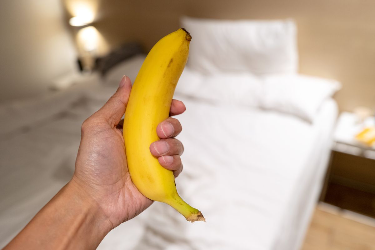 人的手拿著香蕉在酒店的床前