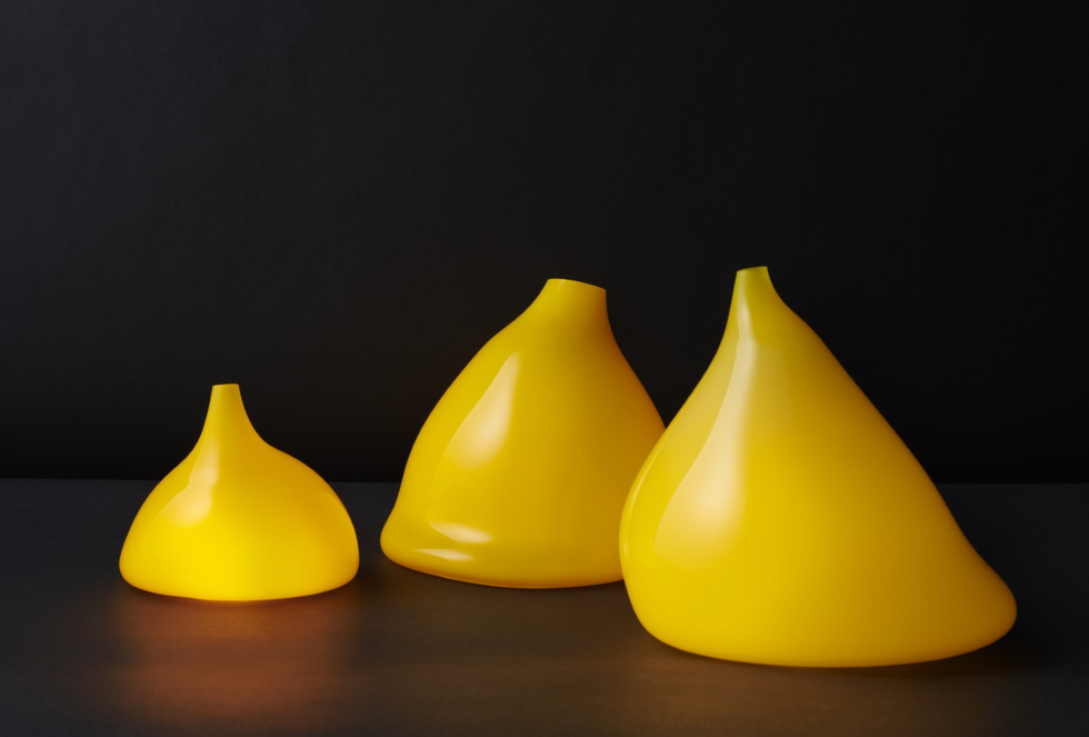 Three yellow, abstract, cone-shaped objects on a black surface.