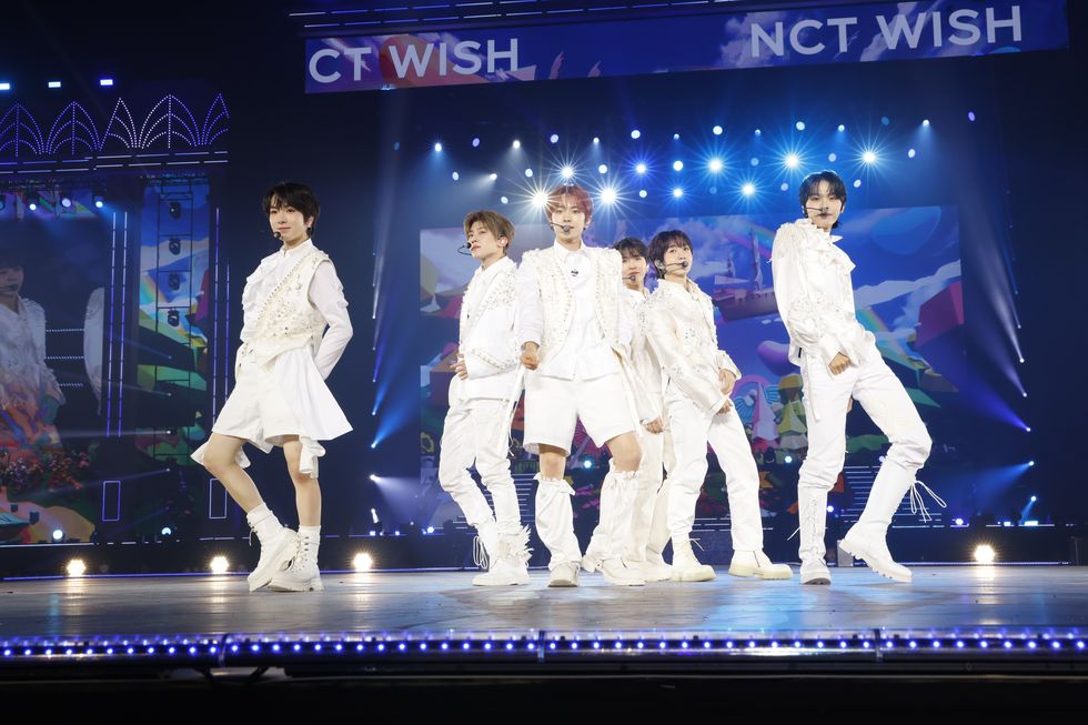 a group of people in white outfits on a stage