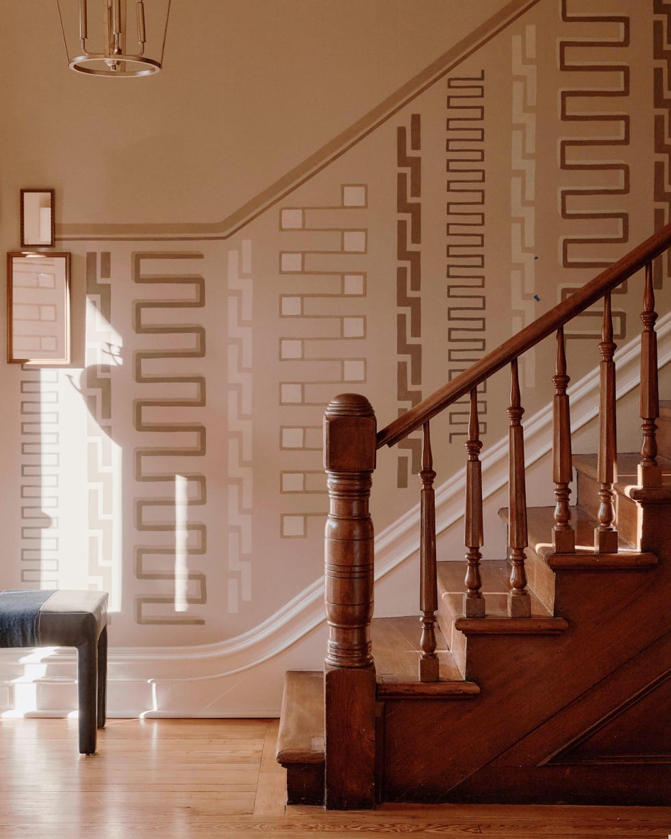 Interior design featuring a staircase, patterned walls, and a bench.