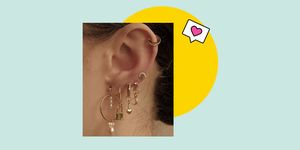 17 ear piercing trends to know in 2020, featuring a woman's ear with gold stacked charm earrings and hoops