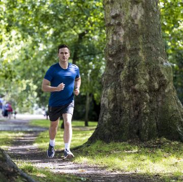 un hombre corriendo en un parque entre árboles