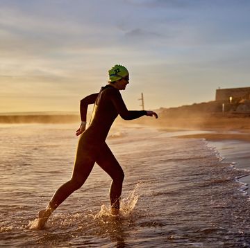 early 50s female triathlete striding out of water at dawn
