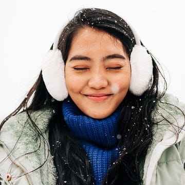 woman in snow with earmuffs and gloves on