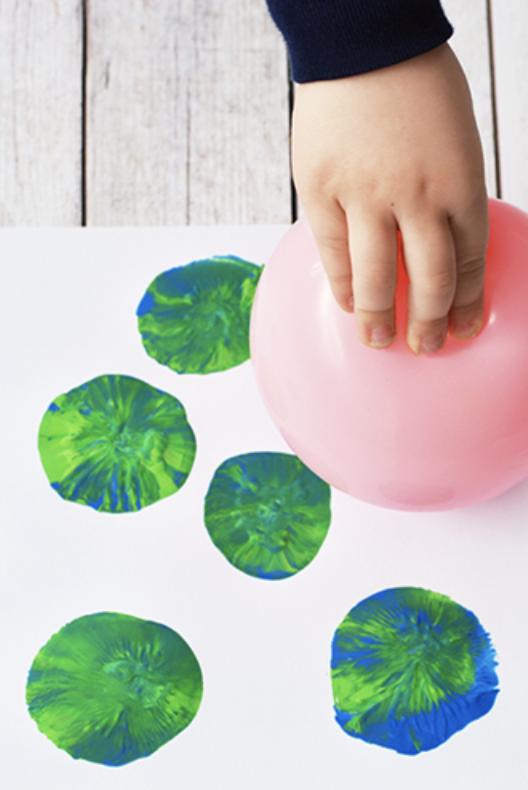 Earth day craft, hand holding pink balloon with paint