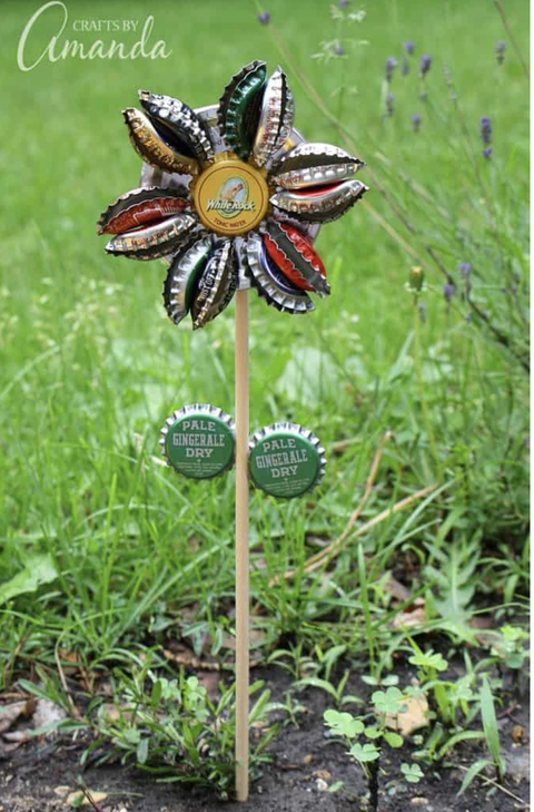 earth day crafts, flower made of bottle caps outside in the grass
