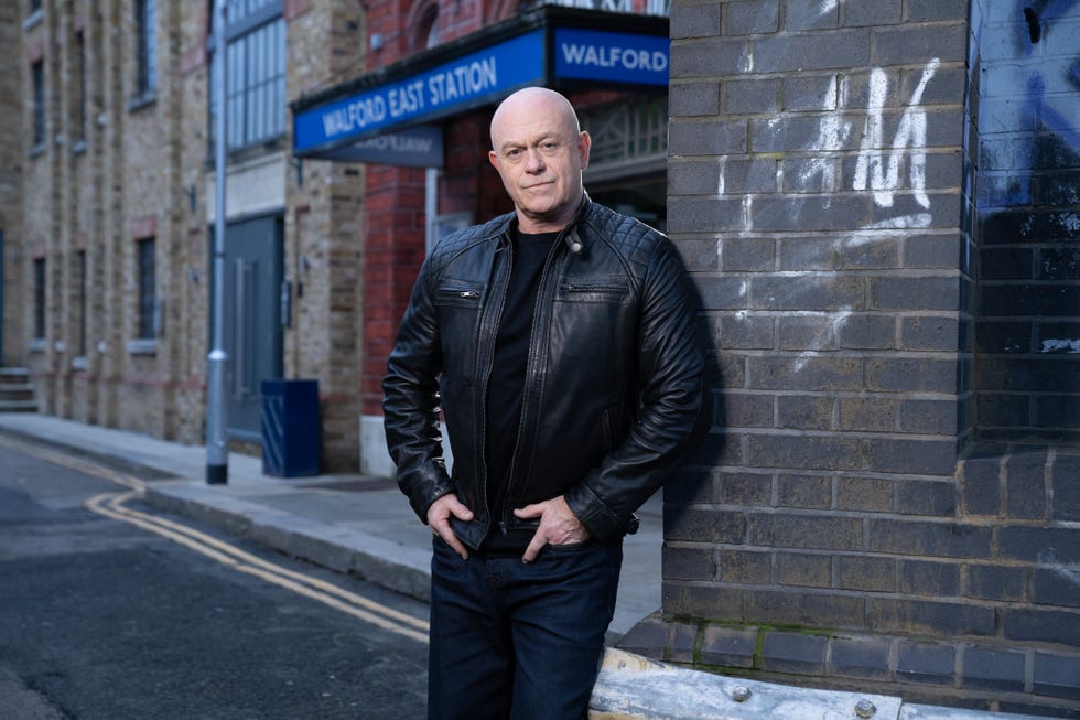 eastenders actor ross kemp as grant mitchell, standing in front of walford east tube station looking serious