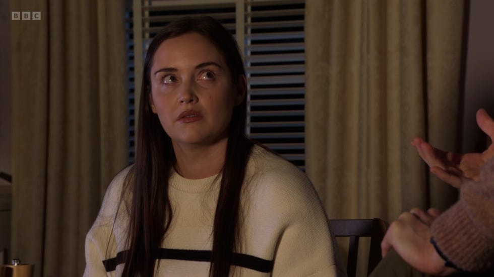 eastenders, lauren branning in a living room, wearing a white jumper with a stressed out look on her face, looking up to her right