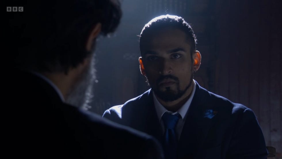 eastenders ravi and nish engaged in a serious conversation, ravi visibly illuminated and nish in shadow