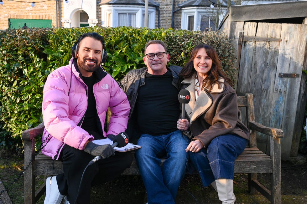 rylan clark with eastenders stars perry fenwick and emma barton sat on a bench in albert square