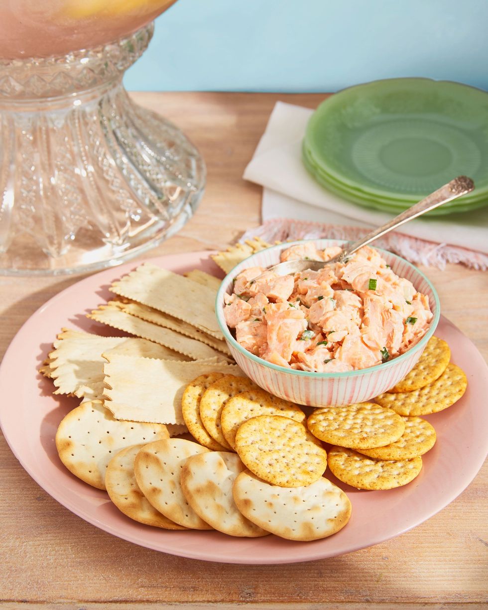salmon rillettes in a bowl with a spoon and on a plate with various crackers for serving