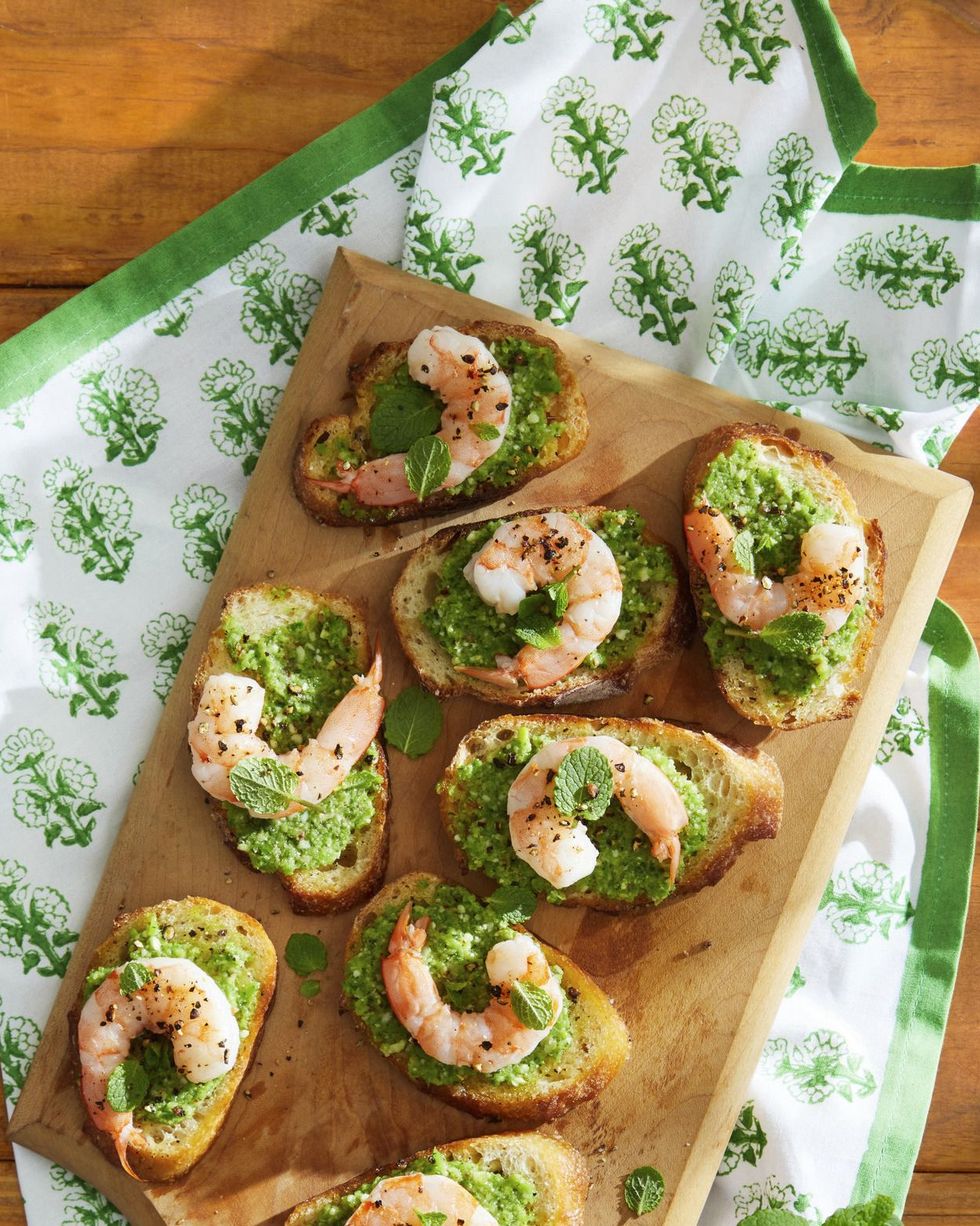 snap pea pesto and shrimp crostini arranged on a wooden serving board