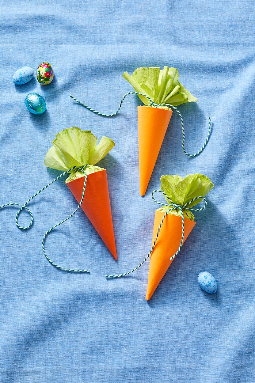 easter basket ideas, three carrot treat cones full of treats with green tissue paper tied with twine