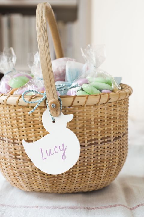 easter basket ideas, white duck shaped name tag that reads lucy on the woven basket's handle