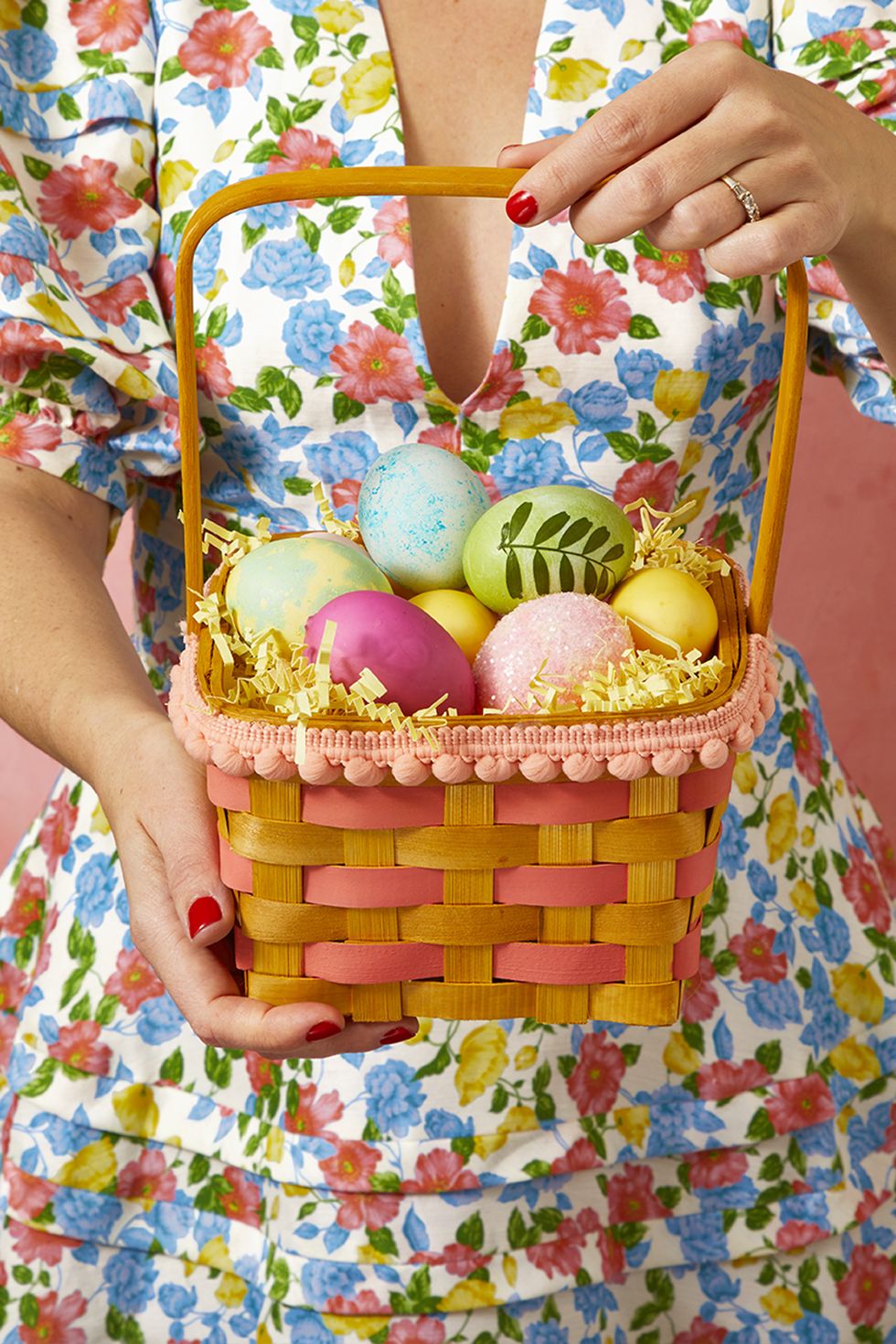 easter basket ideas, woman holding a diy easter basket with hints of pink and a pink pom pom trim