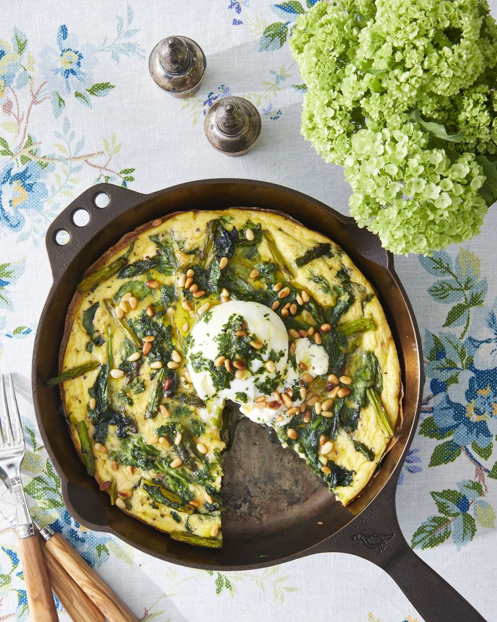 asparagus frittata with burrata and herb pesto in a cast iron skillet with a slice removed
