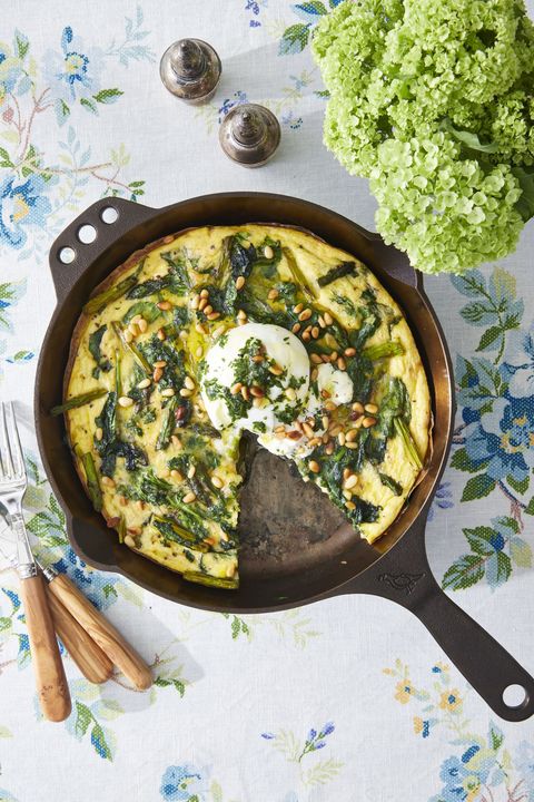 asparagus frittata with burrata and herb pesto in a cast iron skillet with a slice removed