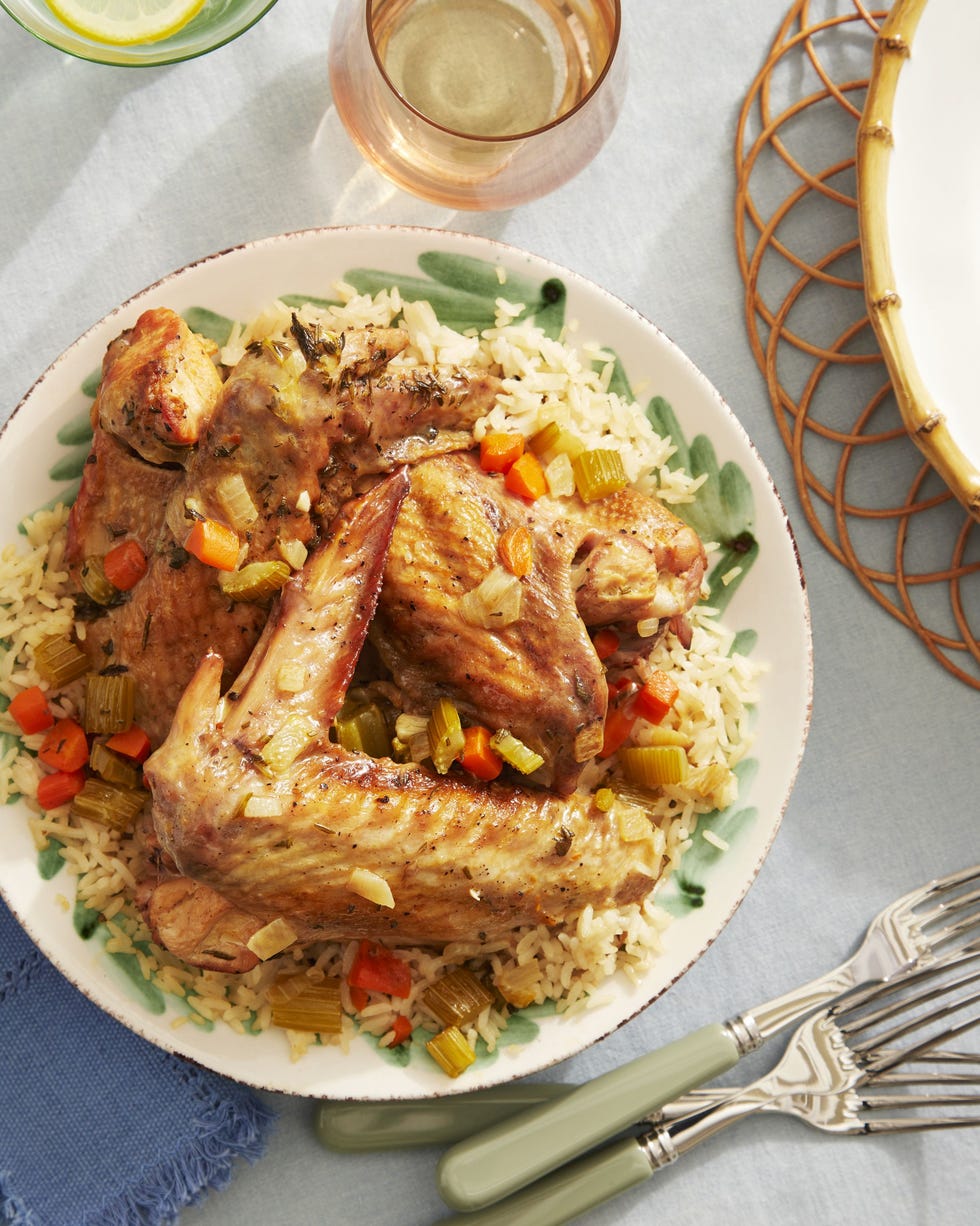 braised turkey wings arranged over rice and chopped veggies on a plate with silverware