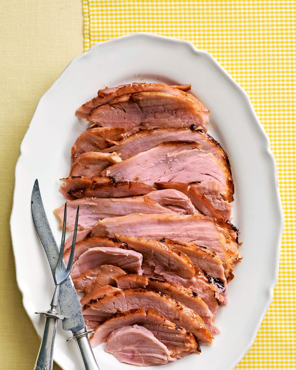 pineapple glazed ham sliced and arranged on a white oval serving plate