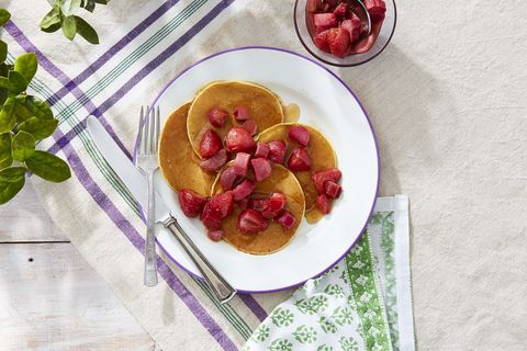 ricotta pancakes with roasted maple rhubarb and strawberries on a white plate with silverware