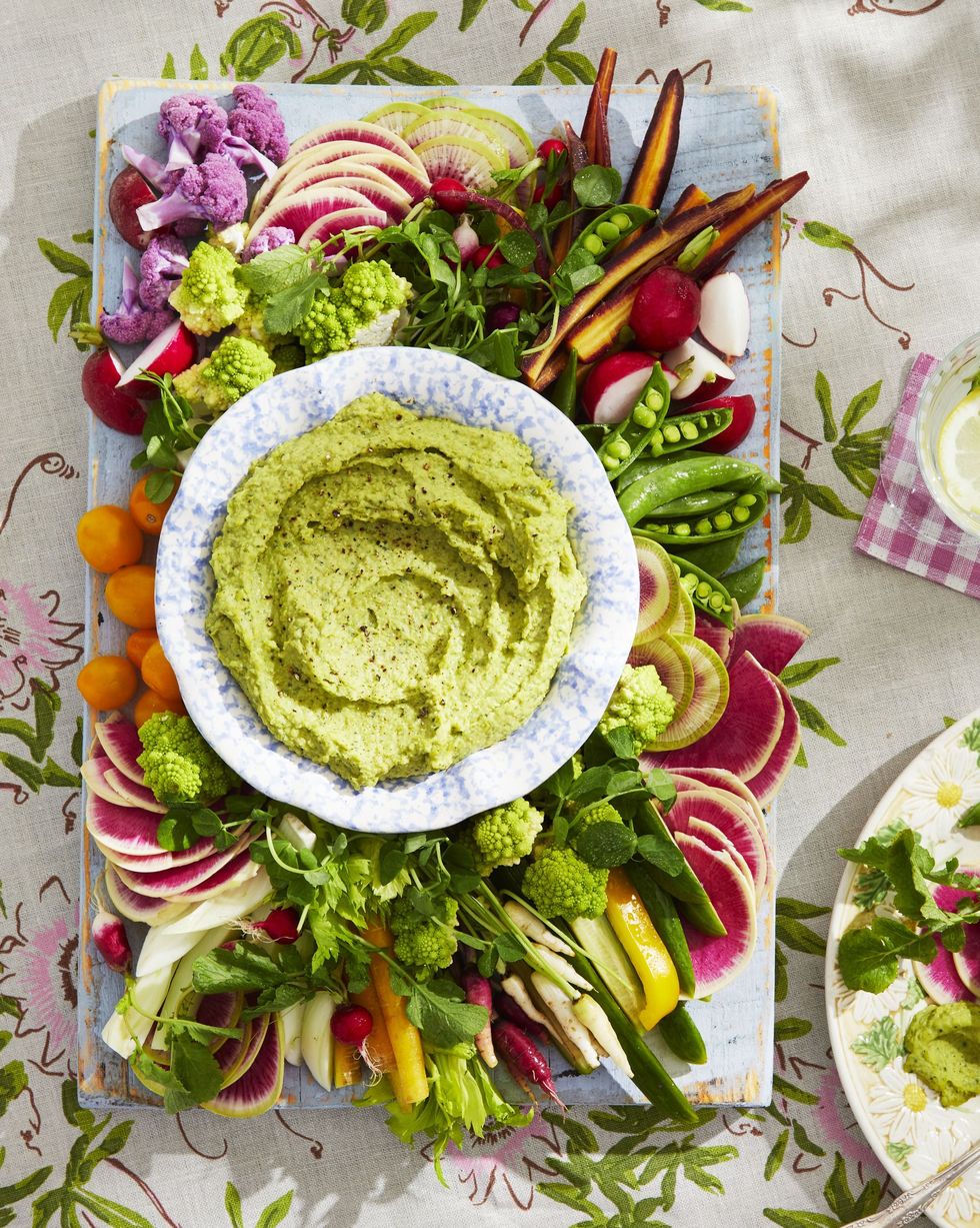 spring crudités board with a bowl of white bean and pea dip in the center
