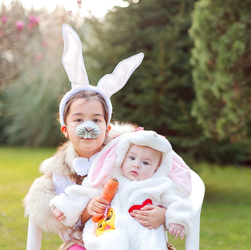 two siblings wearing easter bunny costumes outdoors
