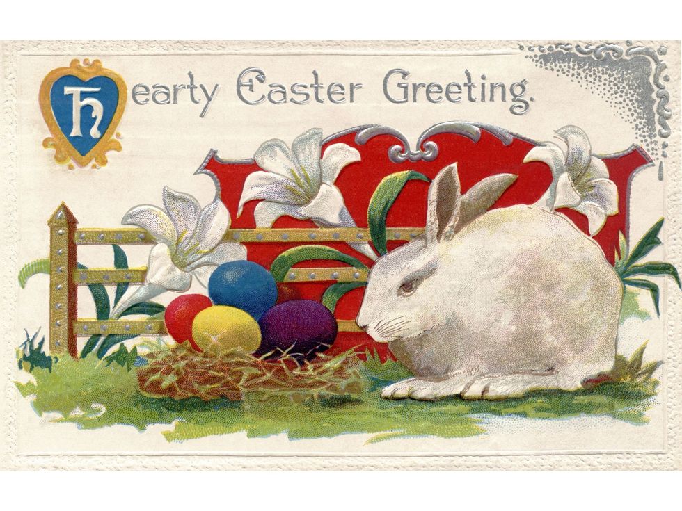 a vintage easter postcard of lilies, a white rabbit and easter eggs