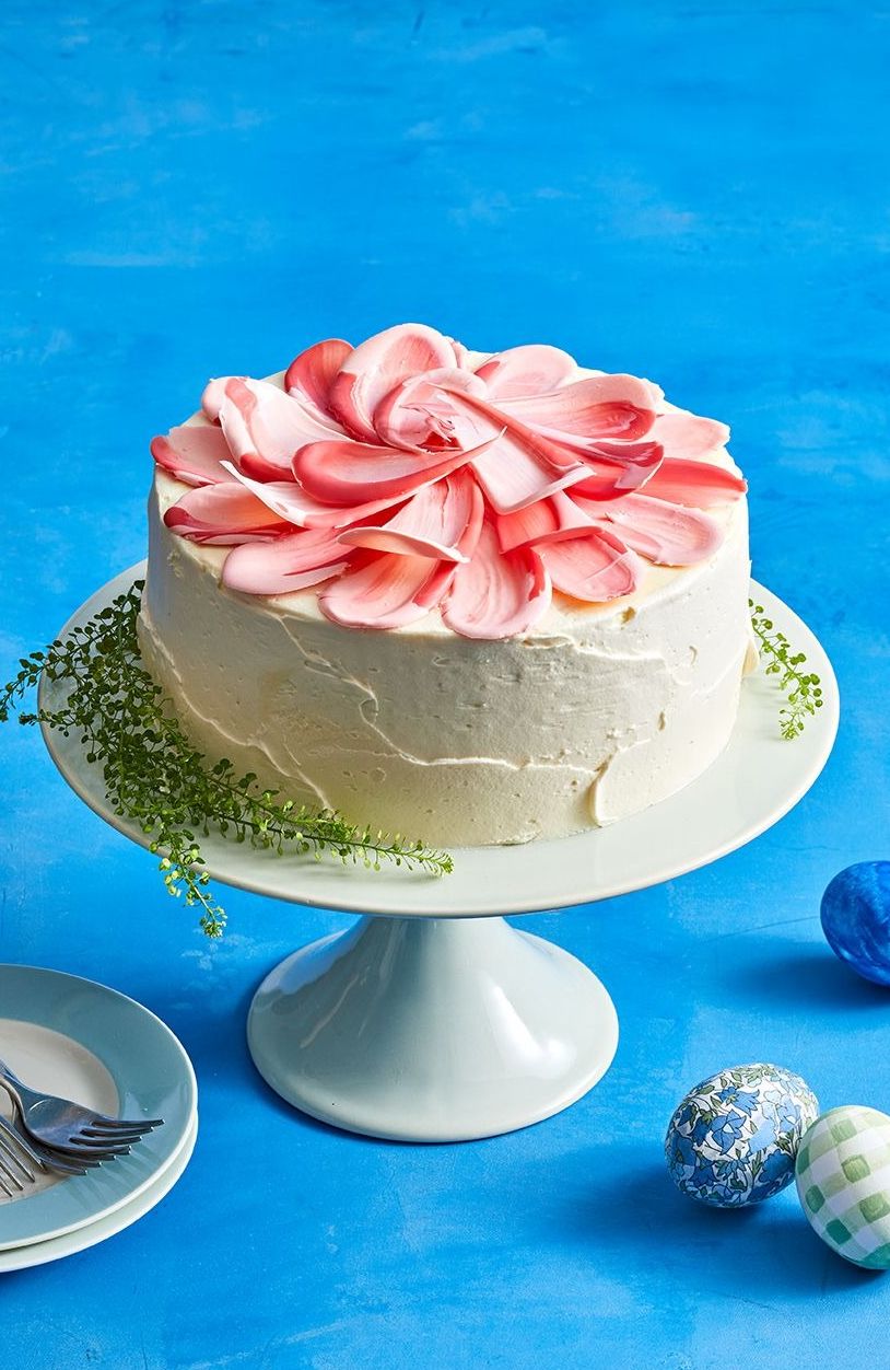 white frosted cake with pink petals on top