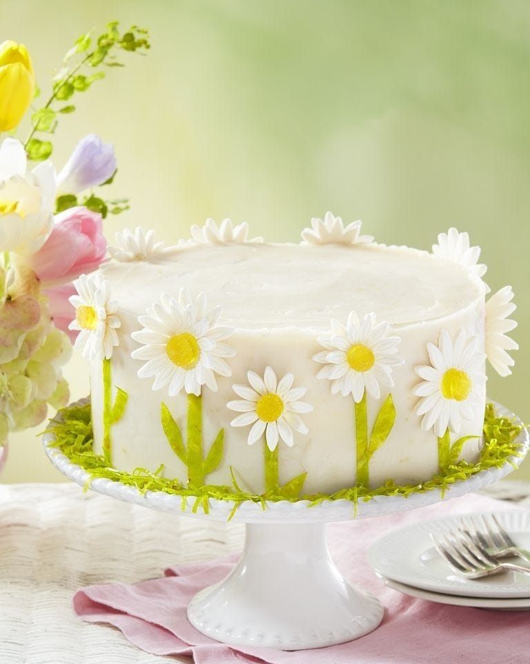 lemon layer cake with lemon frosting and garnished with gumpaste daisies