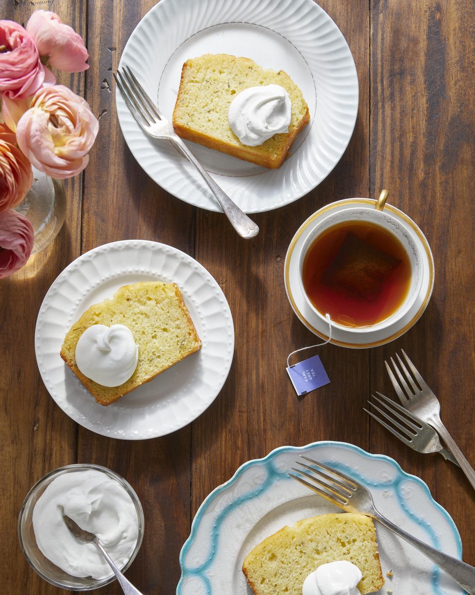 lemon rosemary tea bread cut into slices on white dessert plates with a dollop of whipped cream on top of each slice