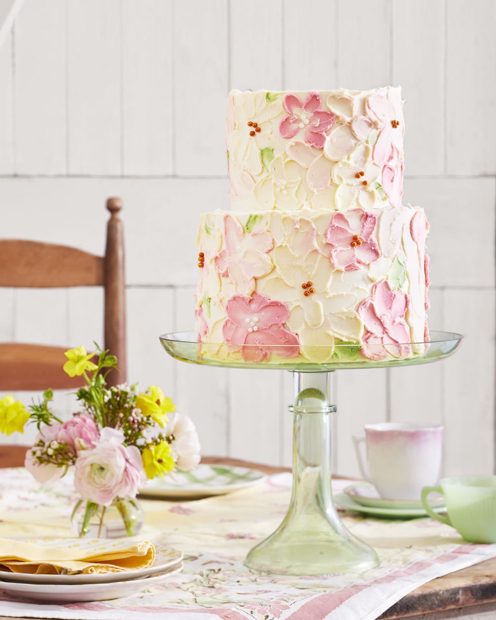 two tiered white velvet cake with white chocolate buttercream frosting with a floral pattern of white and light pink buttercream flowers on the outside