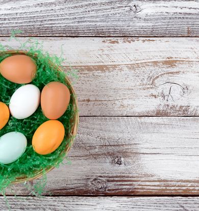 colorful real eggs on artificial green grass in basket for easter background