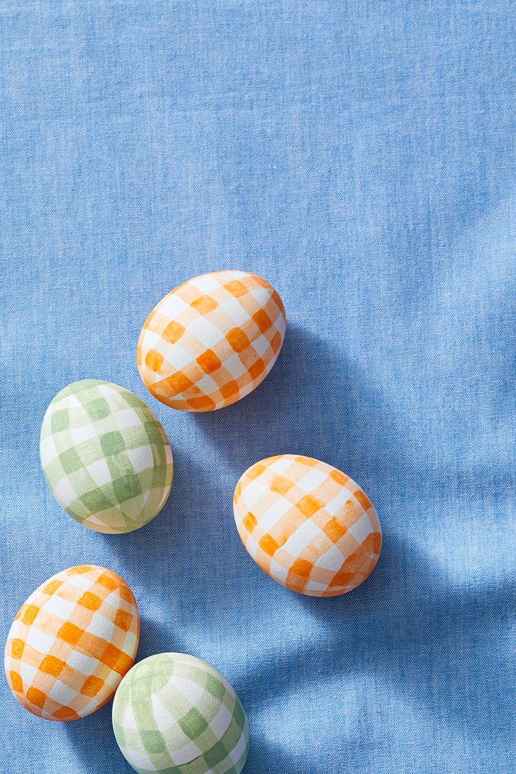 easter crafts, orange and green gingham printed eggs on a blue cloth