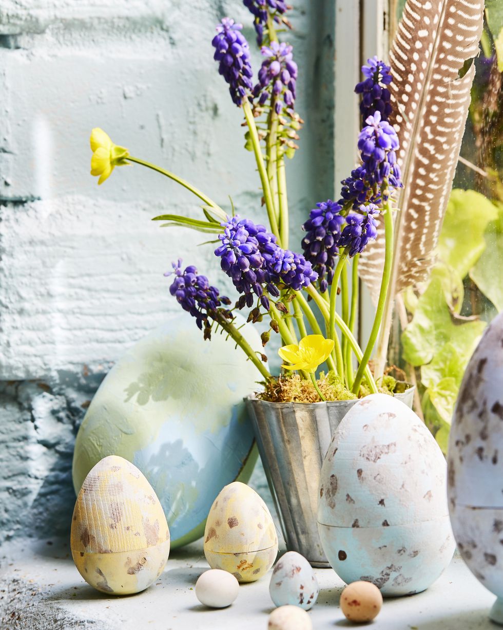 a windowsill with easter eggs and a vase of spring flowers
