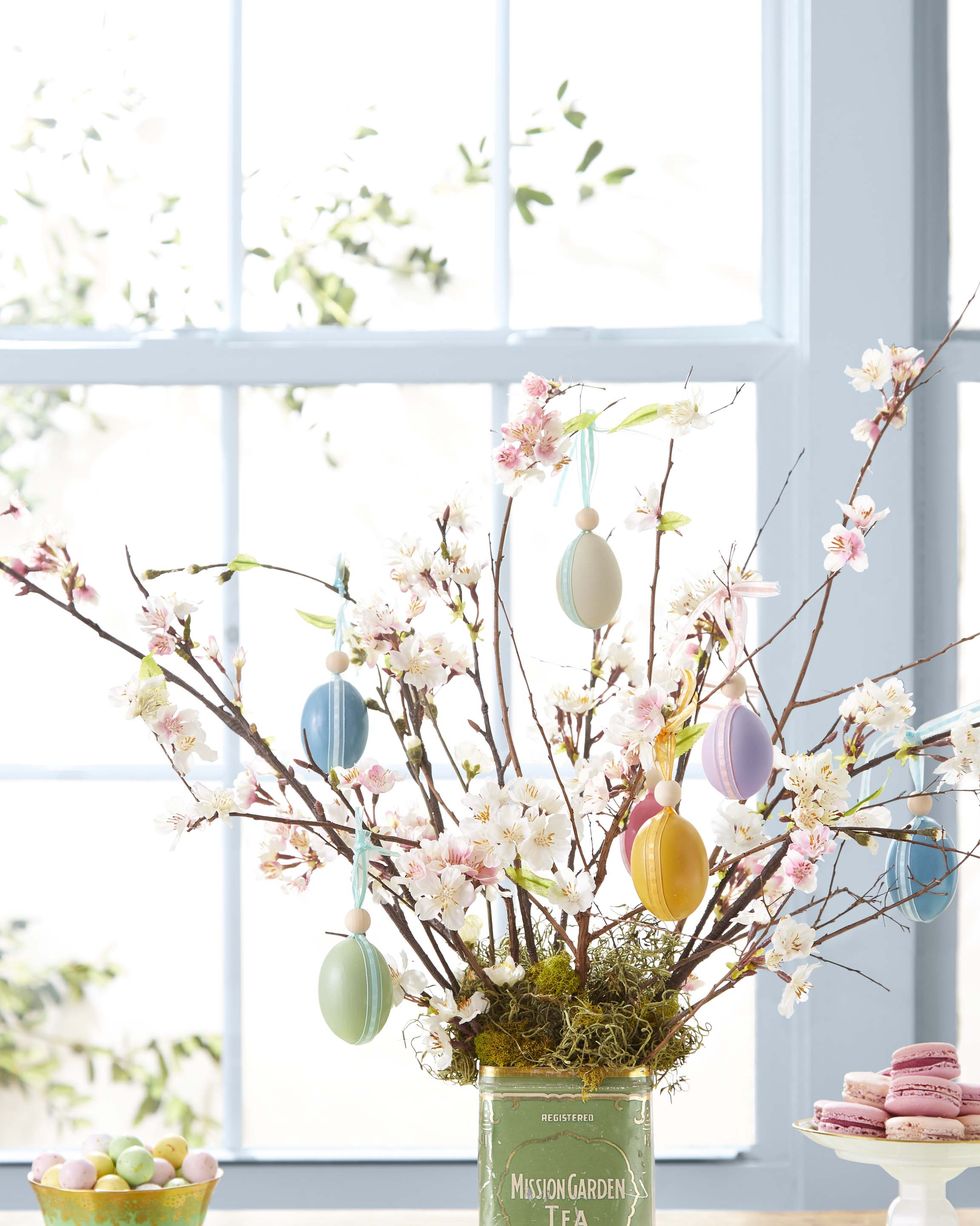 an easter egg tree made of branches and adorned with painted eggs that are hung with ribbon
