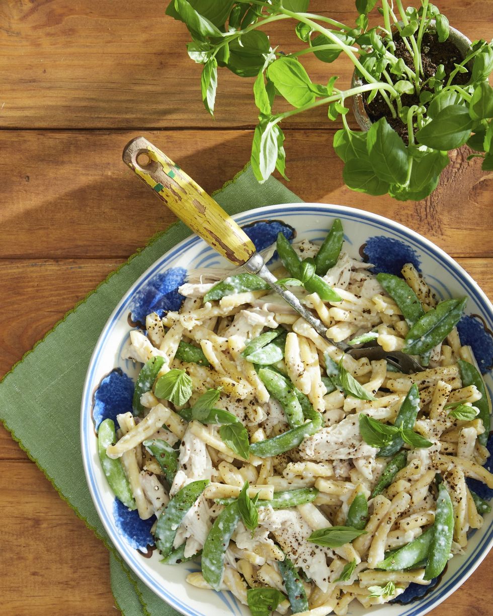 easter dinner ideas chicken and snap pea pasta with creamy garlic basil sauce in a bowl with a green kitchen towel