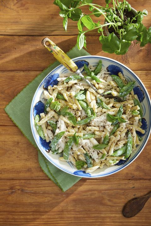 easter dinner ideas chicken and snap pea pasta with creamy garlic basil sauce in a bowl with a green kitchen towel