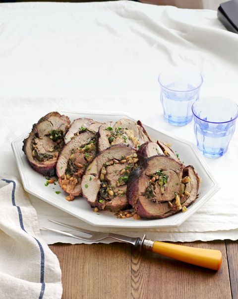 spinach and pine nut stuffed leg of lamb cut into slices and arranged on a white serving dish