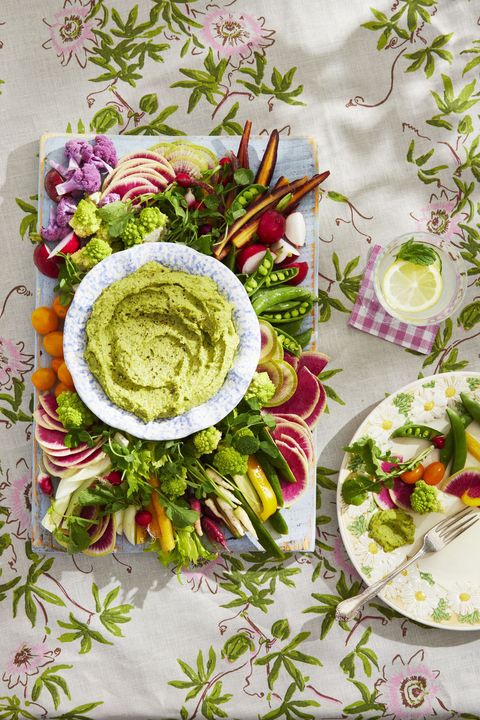 spring crudités board with a bowl of white bean and pea dip in the center and surrounded by various veggies for dipping