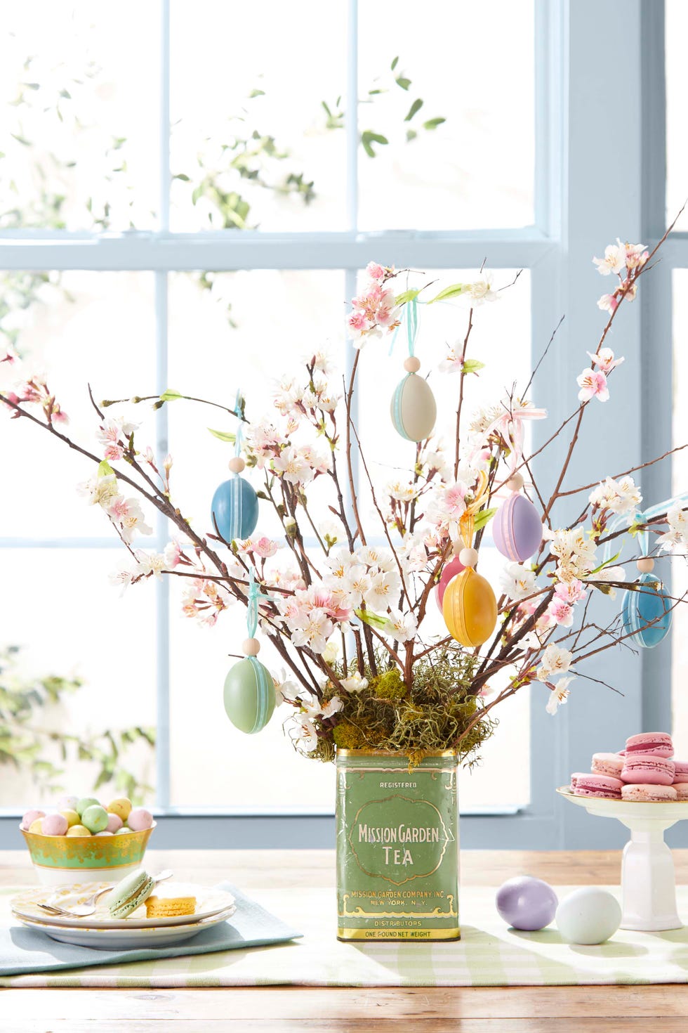 easter egg tree displayed in a vintage tea tin decorated with painted eggs hung with ribbon