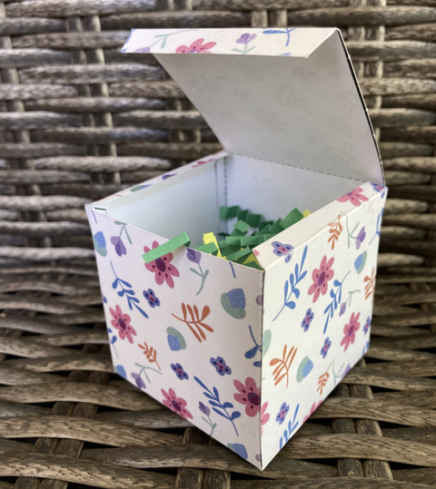 easter egg hunt ideas, white box with flower designs full of green and yellow crinkle paper