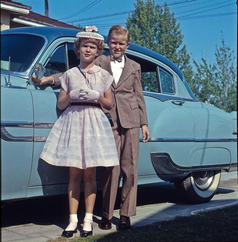 boy and girl standing in front of camera with car