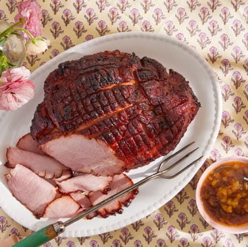 a glazed ham on a plate with some slices cut off