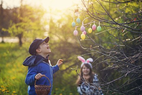 two children looking at easter eggs hanging from tree
