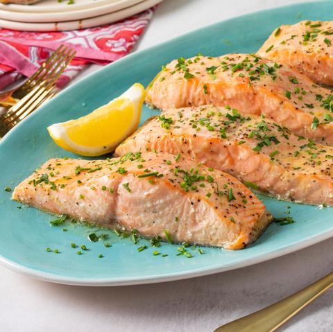 baked salmon with herbs on blue plate lemon