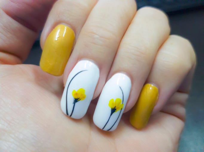 hand showing nails on keyboard art nail design with yellow tulips or daffodils