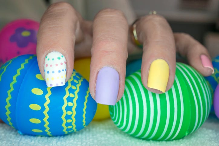 an easter inspired manicure with purple and yellow nails and a white one with coordinating colored dots