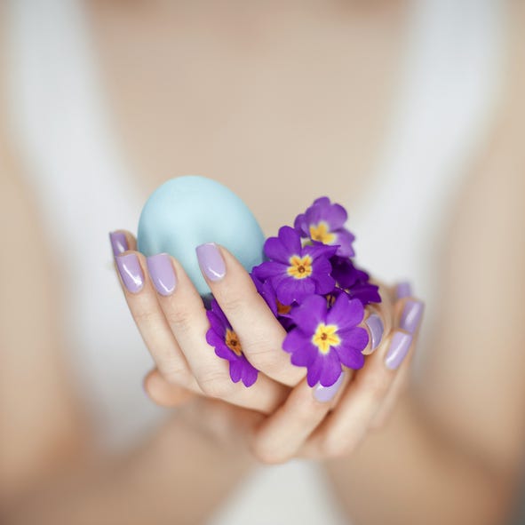 woman hands holding easter egg in turquoise with beautiful fingernails in purple