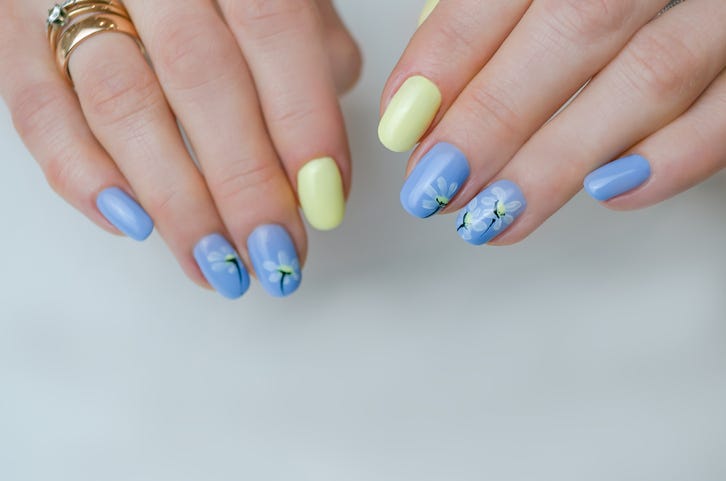 the hands of a young woman the nails are covered with blue and yellow gel polish manicure ideas